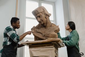 a man and a woman sculpting clay statue